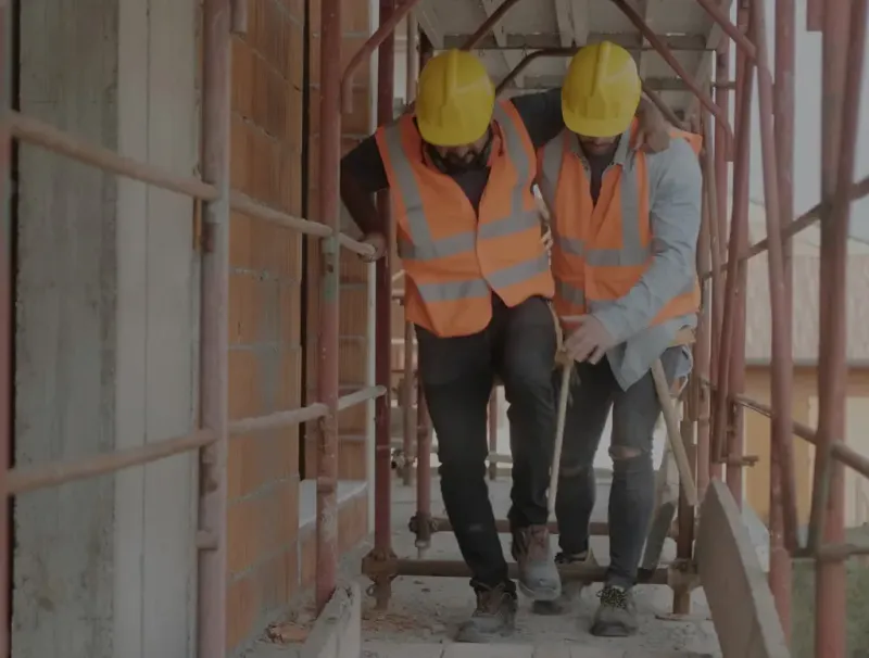 injured worker on a construction job site being assisted by a co-worker